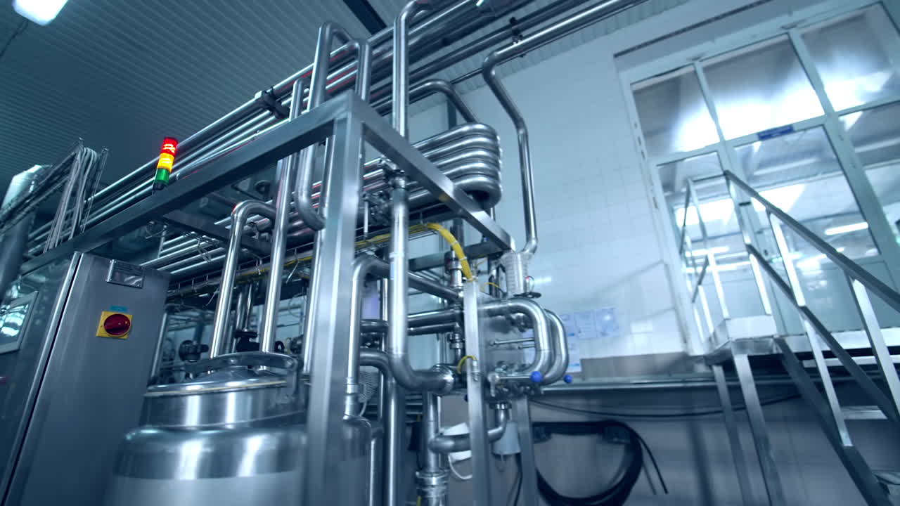 Technological equipment for dairy products manufacturing. Complicated system of pipes intertwining with each other and leading to the cisterns. Close up with gradual distancing.
