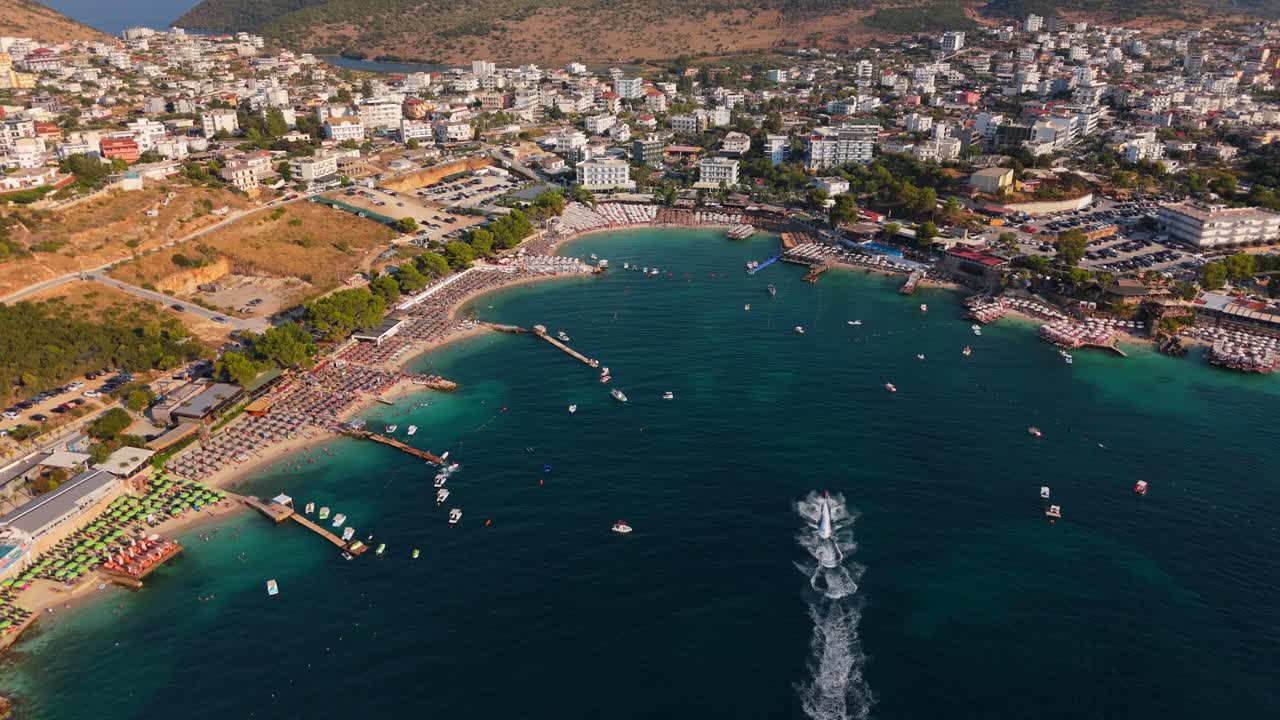 Ksamil, albania coastline with tourists swimming and boats speeding by, aerial view