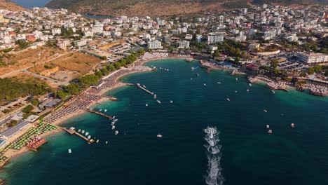 ksamil, costa de albania con turistas nadando y barcos a toda velocidad, vista aérea