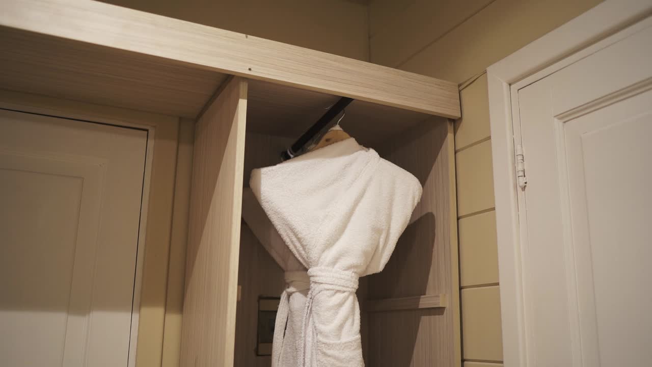 White sauna robe hangs on wooden wardrobe in luxury hotel suite room. Argentina.