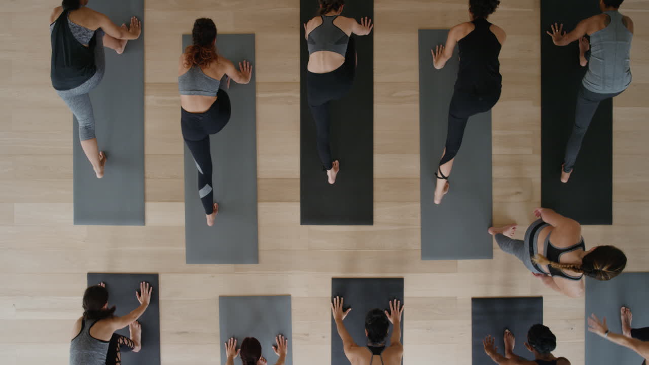 vista aérea instructor de clase de yoga enseñando pose de cobra a un grupo de mujeres que disfrutan de un estilo de vida saludable haciendo ejercicio en el gimnasio