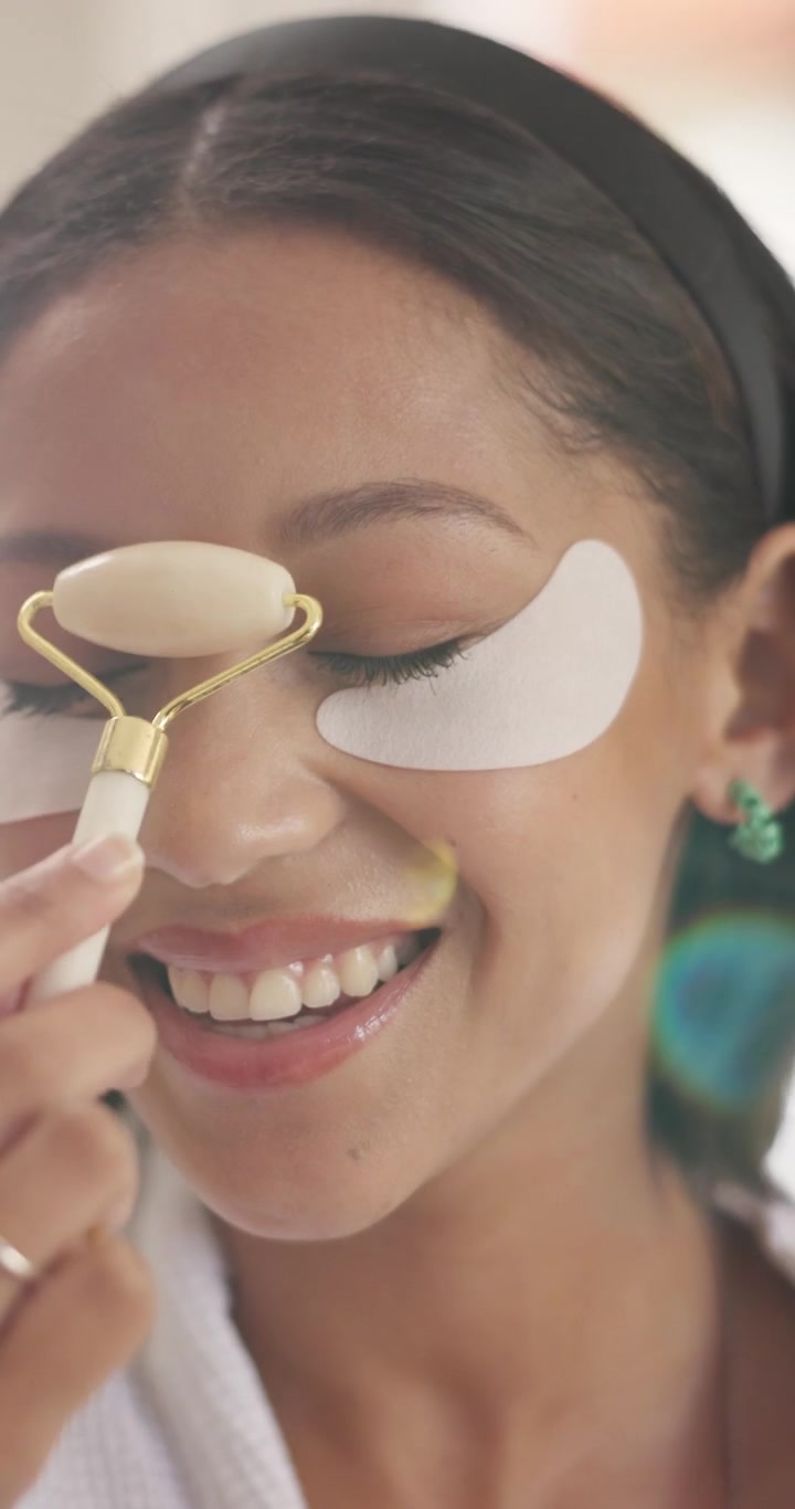 Young Woman Using Jade Roller and Eye Patches for Skincare Routine