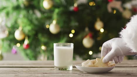 santa claus sumerge la galleta en leche sobre el árbol de navidad y las luces