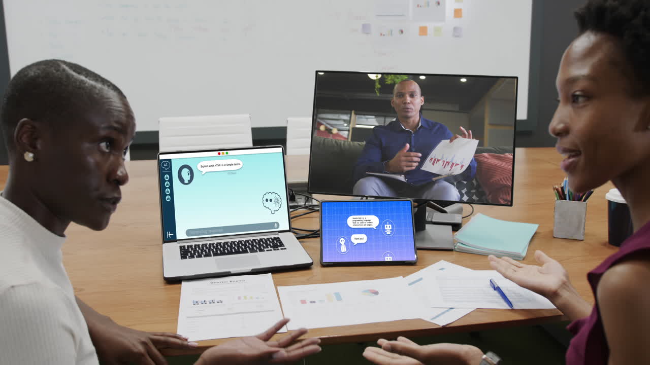 Diverse businesswomen in office using computers with video call and ai messaging on screens