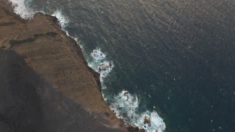 Toma-Aérea-Pov-Relajante,-Muy-Por-Encima-Del-Océano-Azul-Oscuro,-Rango-De-Acantilados,-Inclinación-Hacia-El-Horizonte