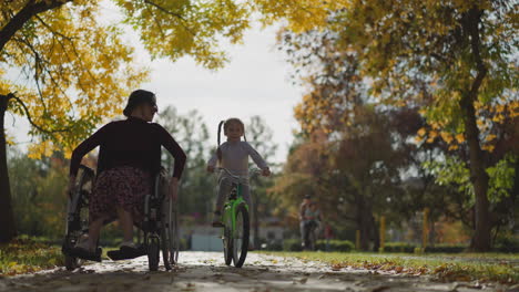 young aunt in wheelchair and niece on bicycle rest in park
