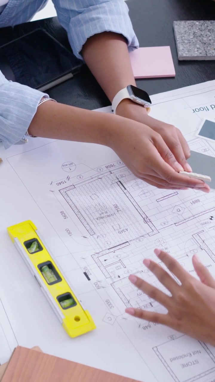 Video verticale: Inizio della revisione, 3 designer in abiti casual che posizionano campioni su una planimetria dell'ufficio per scegliere.