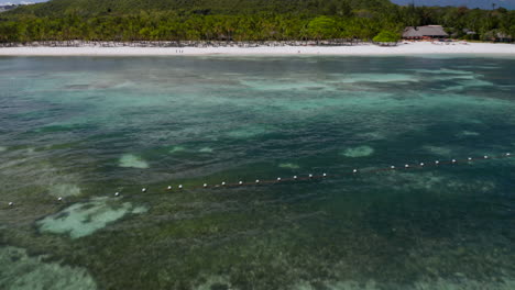 Antena-Inclinada-Hacia-Arriba-Mostrando-Agua-Acuática-Y-Palmeras-En-La-Playa-Privada-Del-Club-De-Playa-De-Bohol,-Isla-De-Panglao