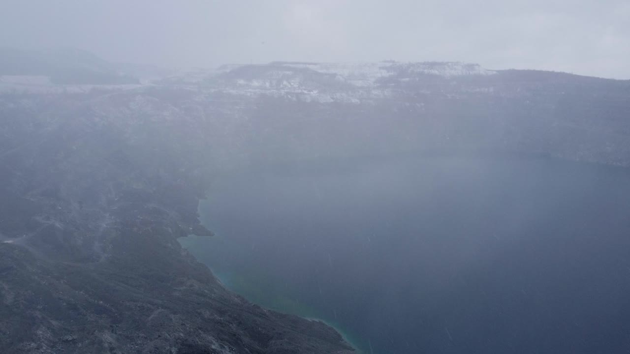 Aerial drone shot of Thetford Mines during snowstorm with lake and snowfall in Quebec, Canada
