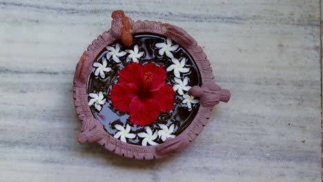 agua sagrada espiritual con flor de hibisco mantenida para las aves en la entrada de la casa desde un ángulo diferente