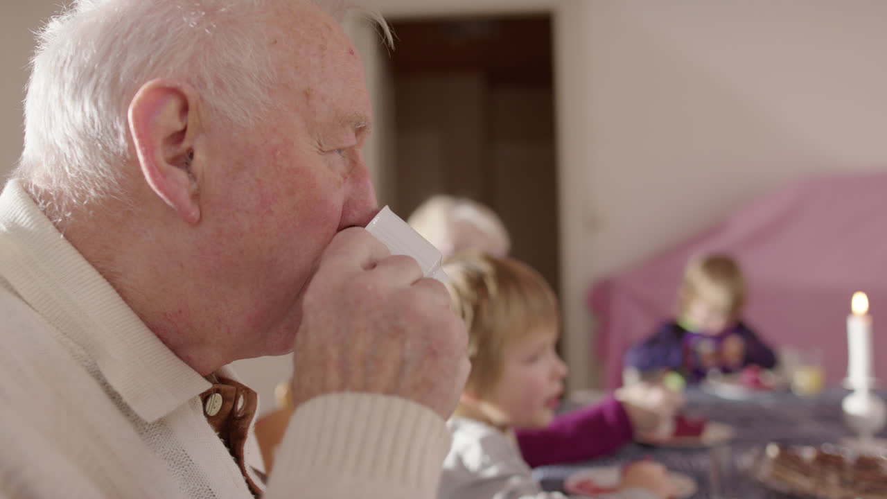 Great-grandfather at family table with great-grandkids sipping coffee, profile