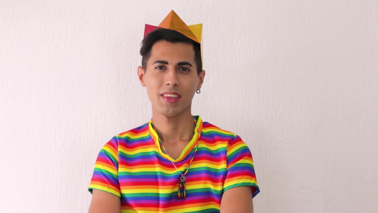 joven gay latino con camiseta arco iris y corona para el desfile lgbtq