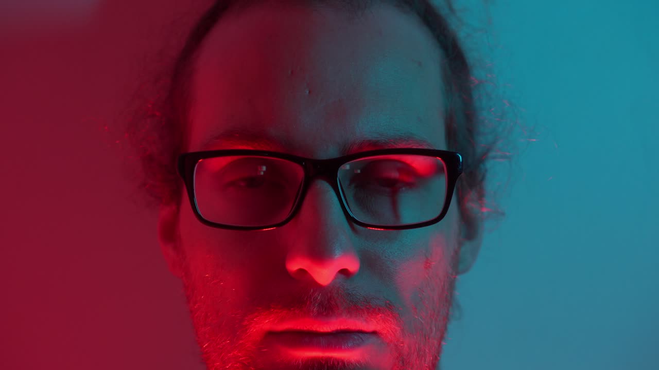 Man with thoughtful expression as eyes close, blue and red lighting adds moody ambiance, subtle shadows as warmth of red awakens man to open eyes
