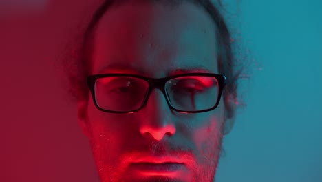 Man with thoughtful expression as eyes close, blue and red lighting adds moody ambiance, subtle shadows as warmth of red awakens man to open eyes