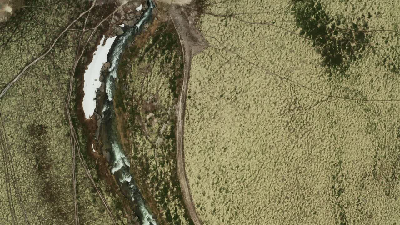 la vista zenital del dron sigue el flujo del río storula debajo de la pasarela y los senderos sinuosos en el parque nacional de rondane, condado de innlandet, noruega.