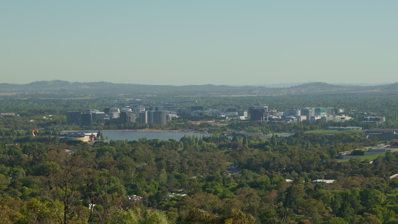 A scenic view of Canberra’s city center, with Lake Burley Griffin in the foreground and high-rise buildings highlighting the urban development of Australia’s capital.