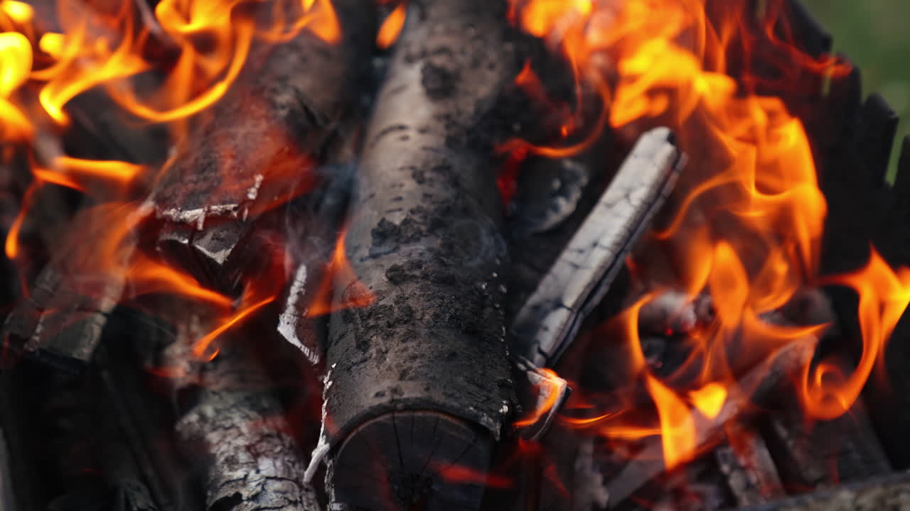 Charcoal in orange flame. Burning out wooden logs in campfire. Embers of wood for barbecue. Smoldered logs background. Close-up