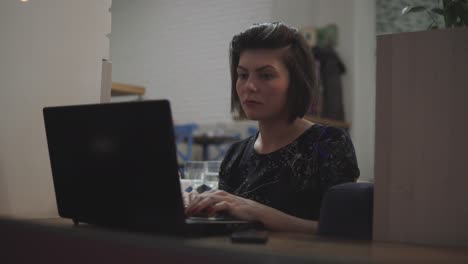 Young-business-woman-sitting-by-the-window-with-a-laptop-and-working