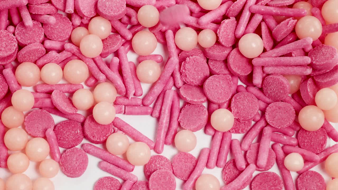 Pink and peach sprinkles cascade in a close-up, creating a vibrant, dynamic scene with a playful mood