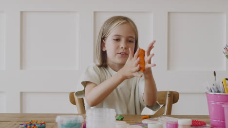 een klein blond meisje dat klei onder haar neus legt alsof het een snor is