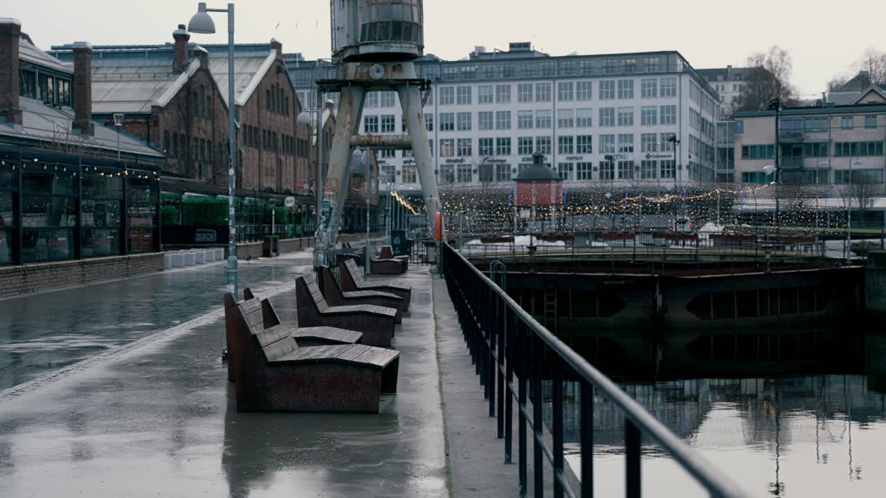 Camera pans over Solsiden, Trondheim, Norway. Misty, cold day. Empty walkways and benches line the quiet district.