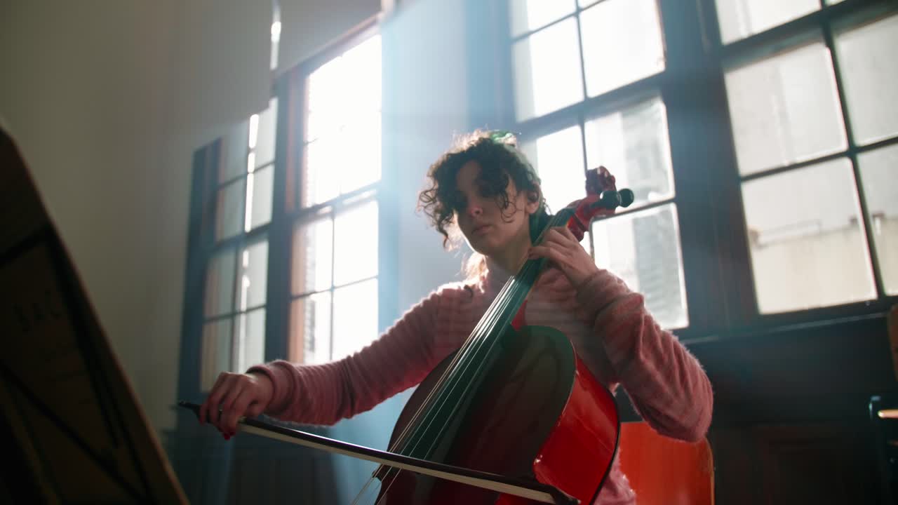 Young Woman Playing Cello with Dramatic Backlight from Window