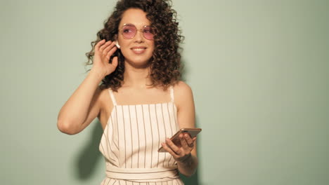 woman with curly hair listening to music on smartphone