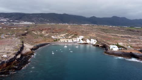 Drone view of a small natural port with fishing boats and with mountains in the background in Puertito de Adeje, Tenerife, Canary Islands, Spain.