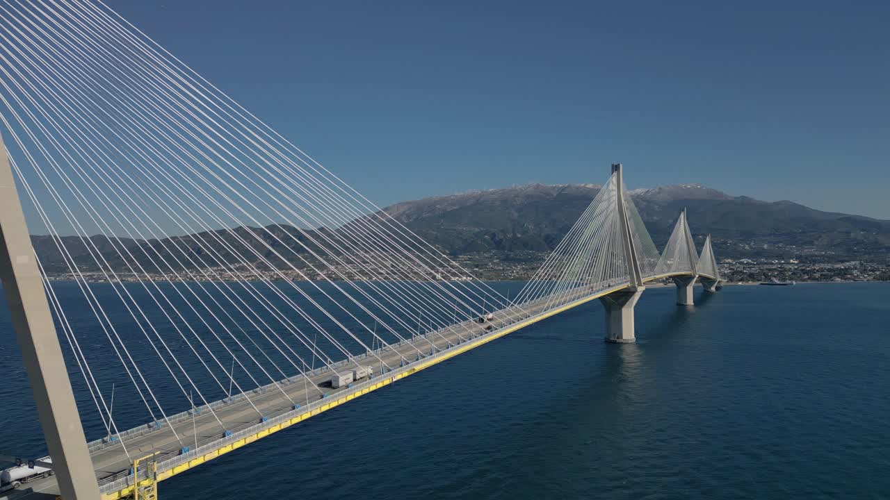 Wide aerial of Rio Andirio Bridge spanning blue waters under clear sky in Greece