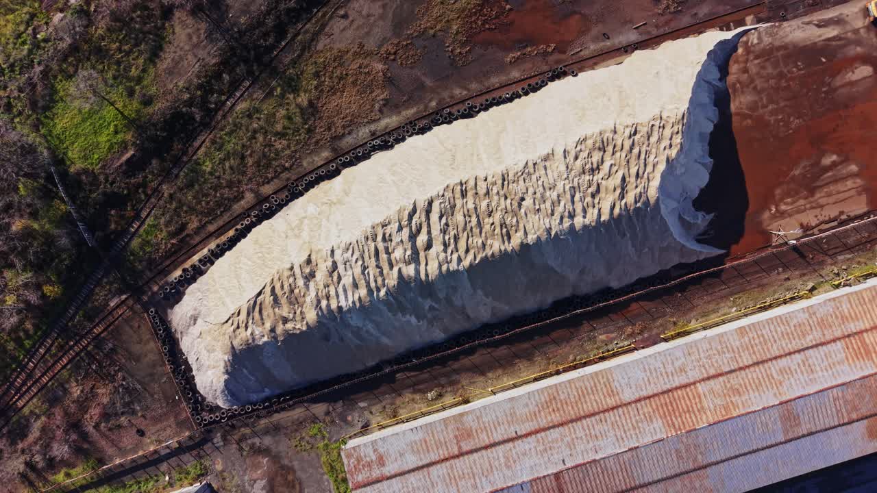 Sandbunke nær industriområde med gammel bygning langs grussti