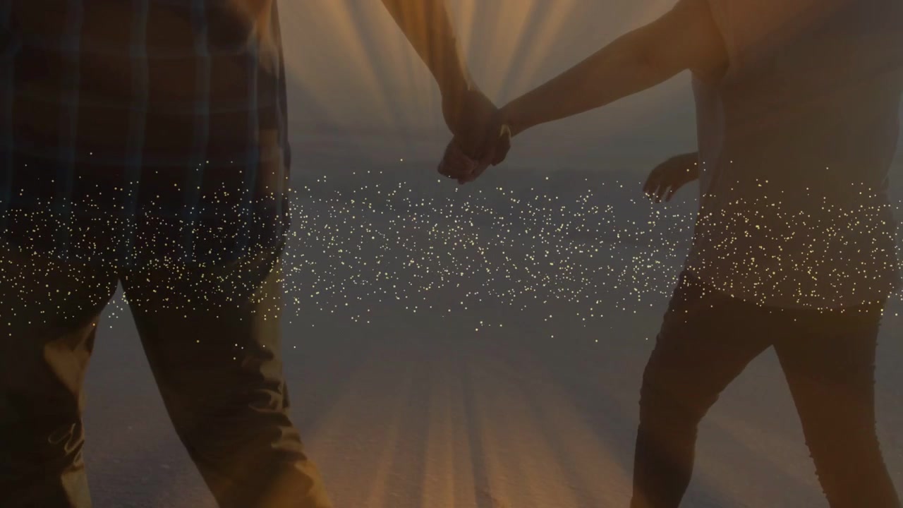 Couple entering frame walking toward horizon, sparkles aligning with joined hands for sunset travel