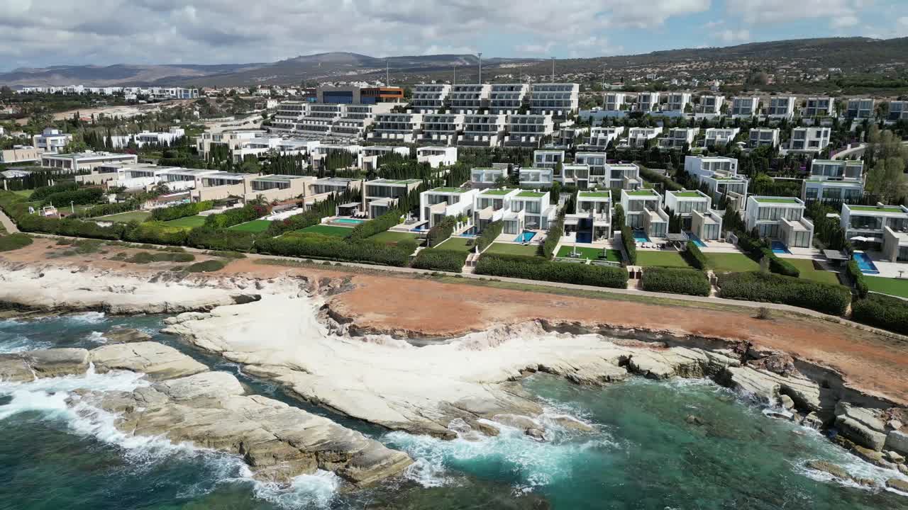 A cinematic drone captures white homes lined side by side, each featuring a private outdoor swimming pool, creating a serene, stylish, and cohesive seaside community.