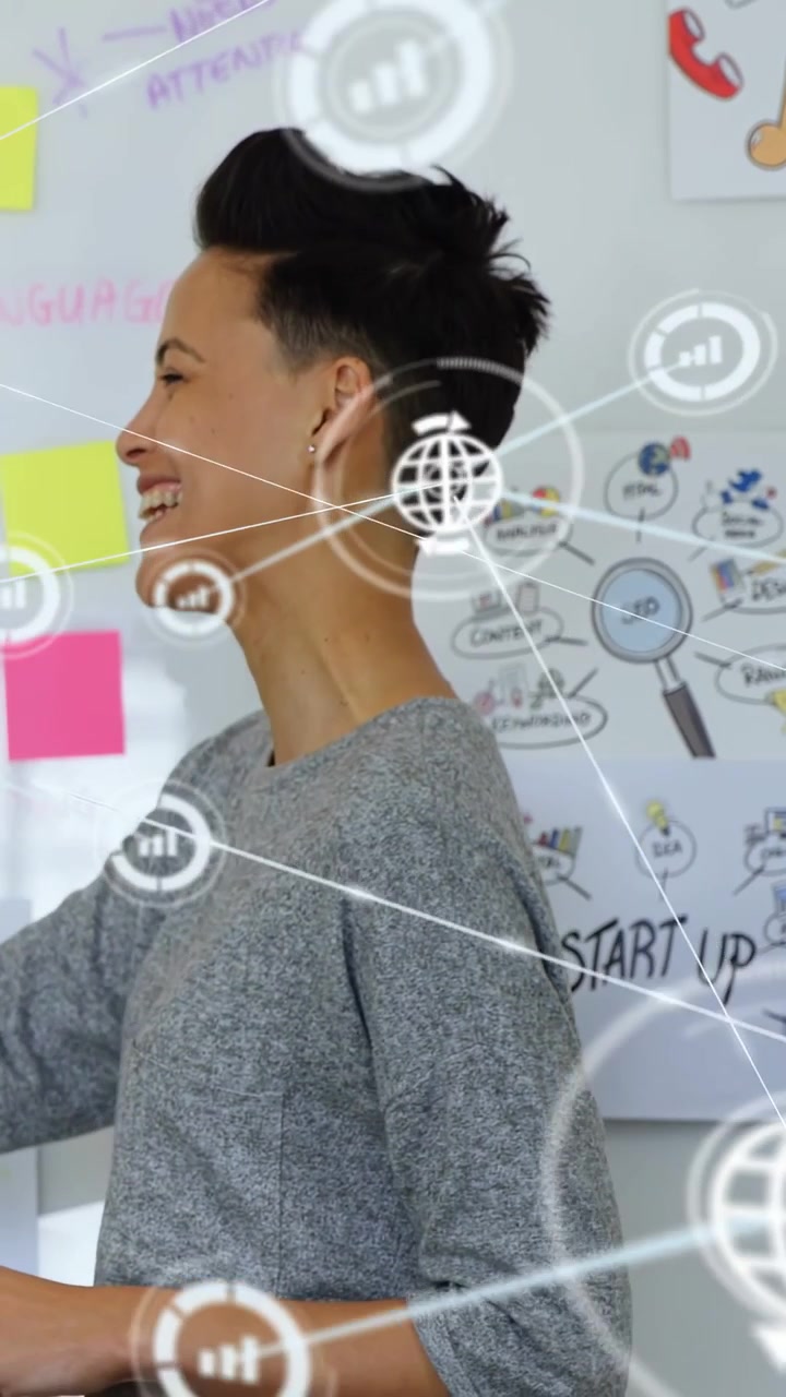 Vertical video: Woman seeing STARTUP sign planning and pointing to SEO notes with icons appearing
