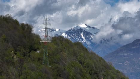 power line towers on alp hilltop with scenic pointed mountain background view