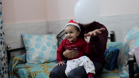 father-and-cute-infant-enjoying-Christmas-eve-celebration-at-home-at-night-from-different-angle