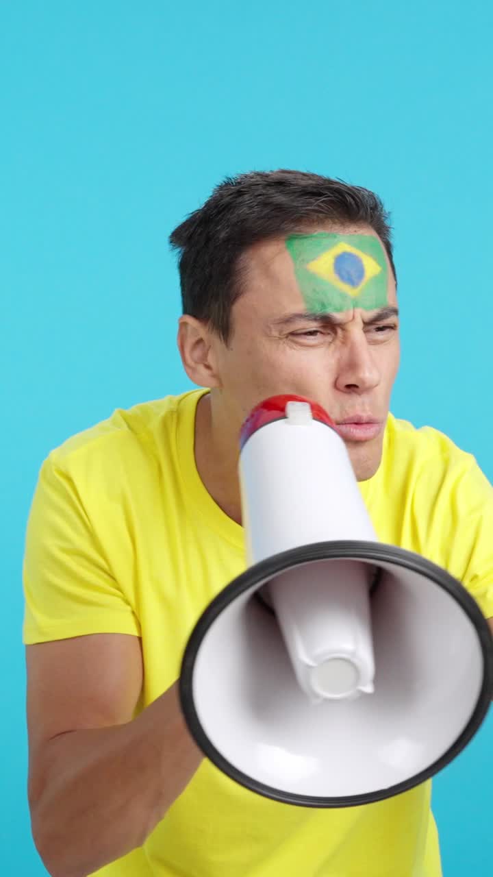 Excited man with brazilian flag on face using a megaphone
