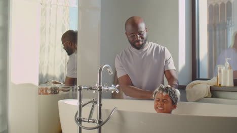 african american father washing little son in bathroom