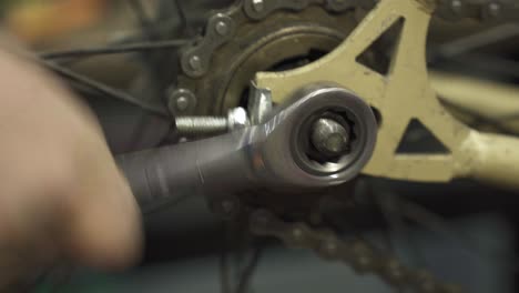 a bicycle mechanic tightening the rear wheel axle screw of a bicycle wheel