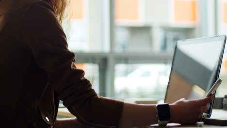 Female-executive-using-mobile-phone-and-laptop