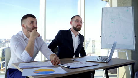 conversation between two businessman. successful entrepreneur men sitting at the table in office center and talk happily on window view background.
