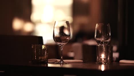 Background-of-two-empty-glasses-of-wine-in-an-elegant-restaurant,-romantic-date-concept-with-no-people,-selective-focus