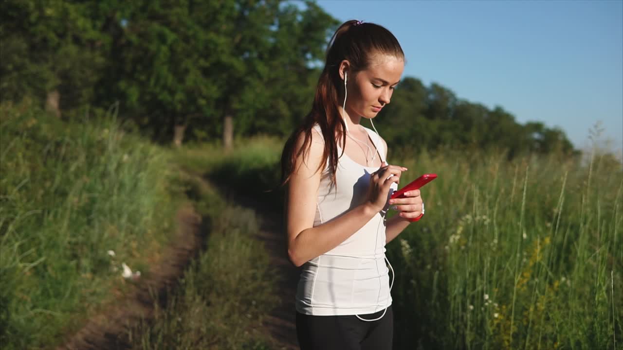Woman jogging outdoors with headphones and phone