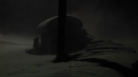 a classic shot of a cabin in a big blizzard or snowstorm at night