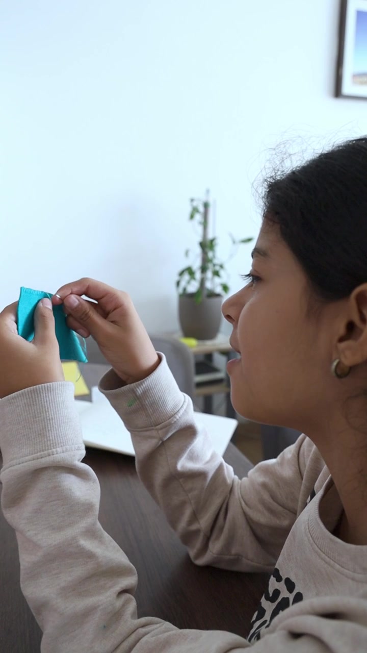 Ragazza concentrata a cucire tessuto blu con ago e filo