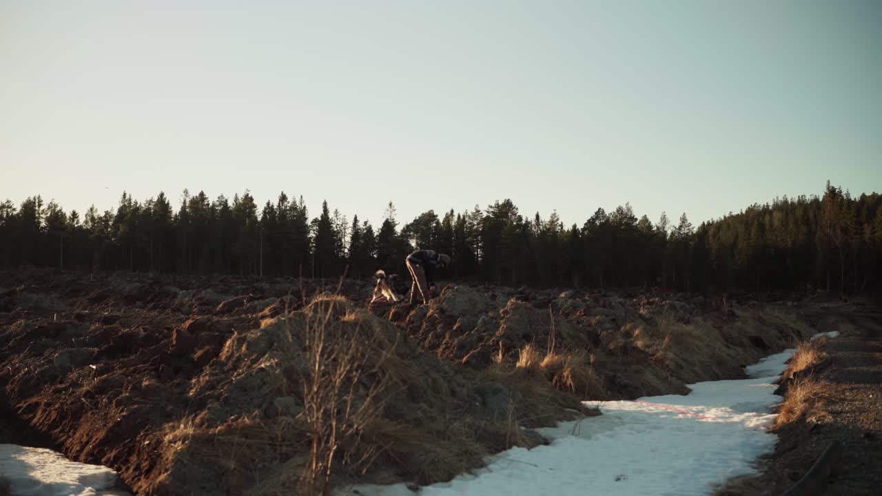 un hombre recogiendo tierra de excavación usando un cubo en la naturaleza rural