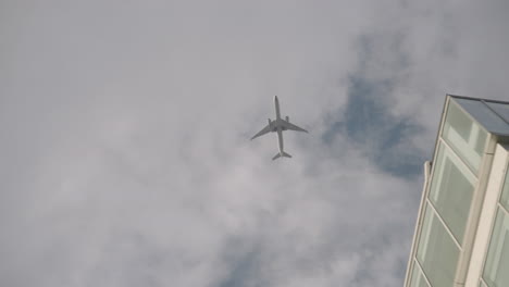 Airplane-Flying-In-The-Sky-With-White-Clouds-Over-City-Buildings-In-Tokyo,-Japan