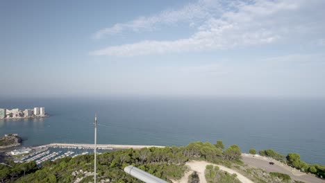 close-up 4k discover vertical drone view next to a spinning marine radar on top of a hill in oropesa del mar, facing the blue mediterranean sea, spain