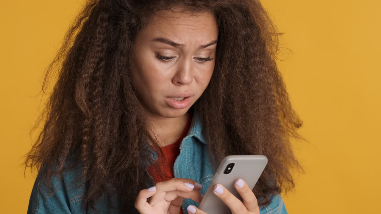 Confused Caucasian curly haired woman scrolling on smartphone.