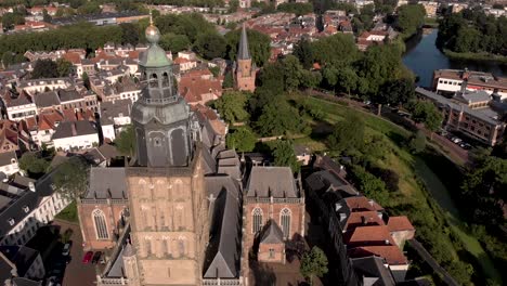 Top-down-view-and-slow-aerial-reveal-of-Walburgiskerk-cathedral-in-medieval-Hanseatic-town-of-Zutphen-in-The-Netherlands-with-the-Drogenapstoren-in-the-background