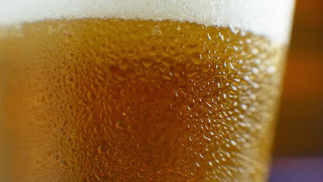 Macro-shot-of-a-beer-glass-with-cold-beer-bubbles-rise-in-the-glass.-Slow-motion-beer-bubbles